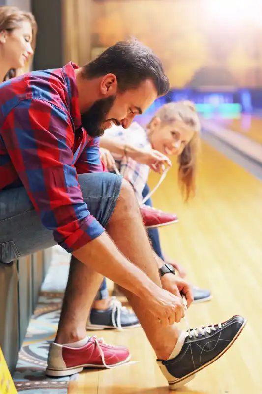 Picture showing friends putting on bowling shoes